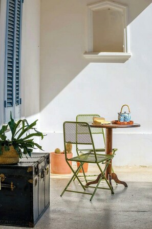 A room with a table, a chair, a potted plant, and a suitcase.