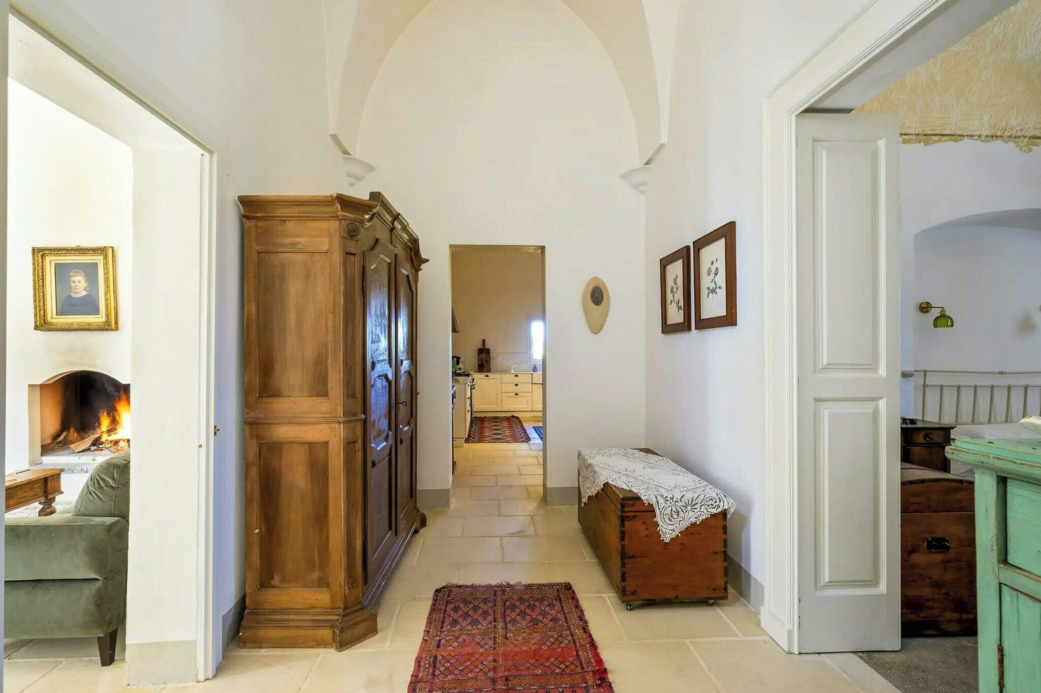 A hallway with a fireplace, wooden furniture, and a patterned rug.