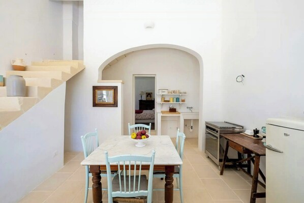 A compact kitchen with a dining area, a refrigerator, and a stove.