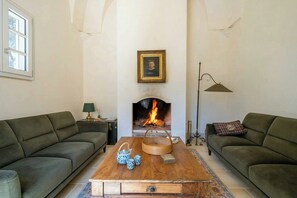 A living room with two sofas, a wooden coffee table, a fireplace, a framed picture, and a floor lamp.