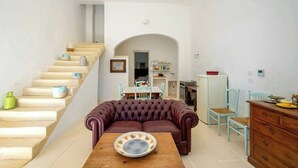 Uma sala de estar com um sofá, uma mesa de jantar e uma escada.