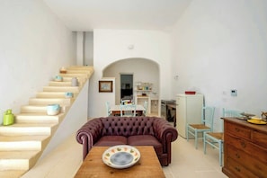 A living room with a sofa, a dining table, and a staircase.