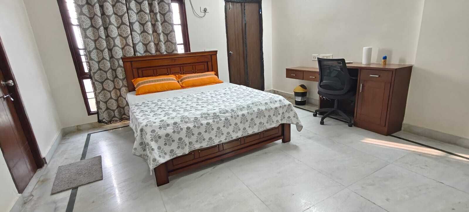 A bedroom with a bed, a desk, and a wardrobe.