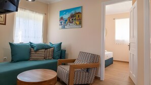 Ein Wohnzimmer mit einer Couch, einem gemusterten Sessel, einem Holztisch und einem Bild an der Wand.