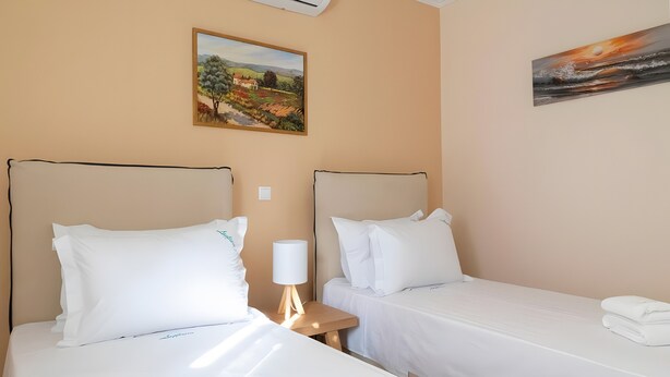 Ein Hotelzimmer mit zwei Einzelbetten, einem Nachttisch mit Lampe und einem Bild an der Wand.