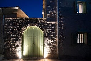 A building with a green arched entrance, a stone wall, and a small window with shutters. - Apartment 'Dervisia Stone Houses 1' with Lake View, Wi-Fi and Air Conditioning (Lazarata)