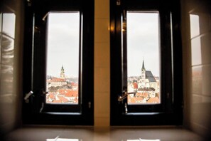 Two windows with a view of a cityscape, including a prominent tower and a church.
