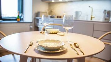 Een ronde eettafel met een witte tafelkleed, een wijnglas, een bord en bestek.