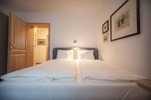 A hotel room with a bed, a nightstand, a wall-mounted lamp, and framed pictures.