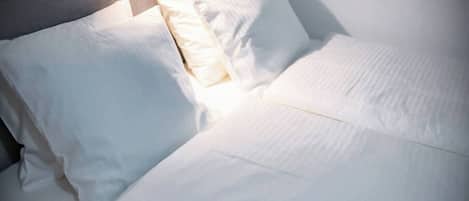 Un lit bien fait, avec du linge de lit blanc et des oreillers.