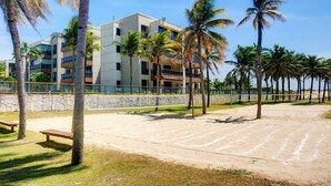 Ein Hotel direkt am Strand mit mehreren Etagen, Palmen und einem Sandstrand.