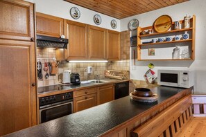 A kitchen with wooden cabinets, a microwave, a coffee maker, and a sink.