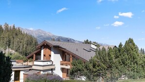 Ein modernes Chalet mit schrägem Dach, Holzfassade und Balkon.