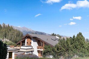 Ein modernes Chalet mit schrägem Dach, Holzfassade und Balkon.