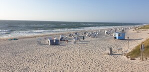 Una playa arenosa con numerosas cabañas de playa y una torre de salvavidas.