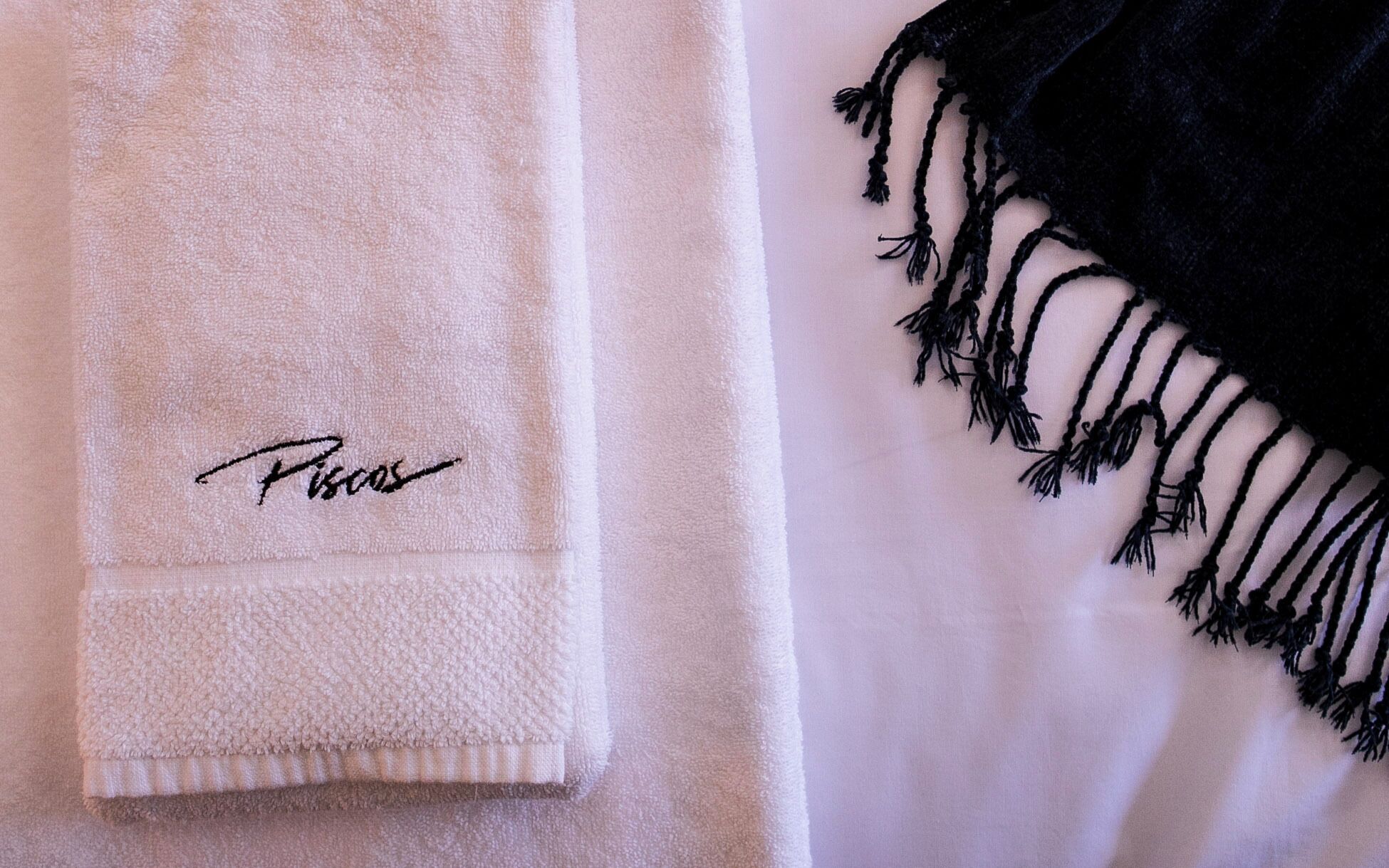 Una toalla blanca con un diseño y una toalla negra con flecos.