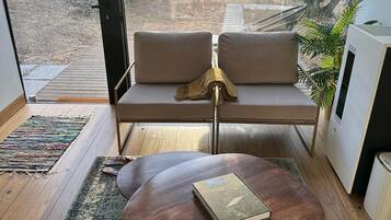 A modern living room with a sofa, a coffee table, and a view of a garden through large windows.