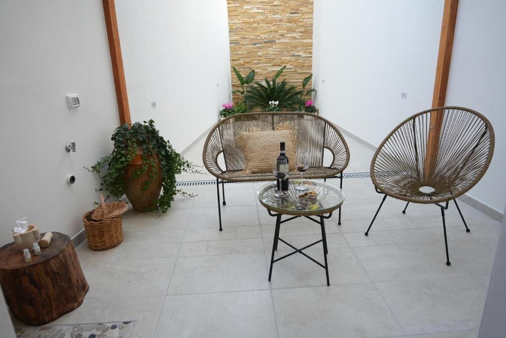 Un pequeño patio con sillas de mimbre, una mesa de vidrio y una planta en maceta.