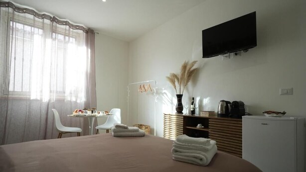 A hotel room with a bed, a desk, a chair, a TV, and a minibar. - B&B CasaLù (Sammichele di Bari)