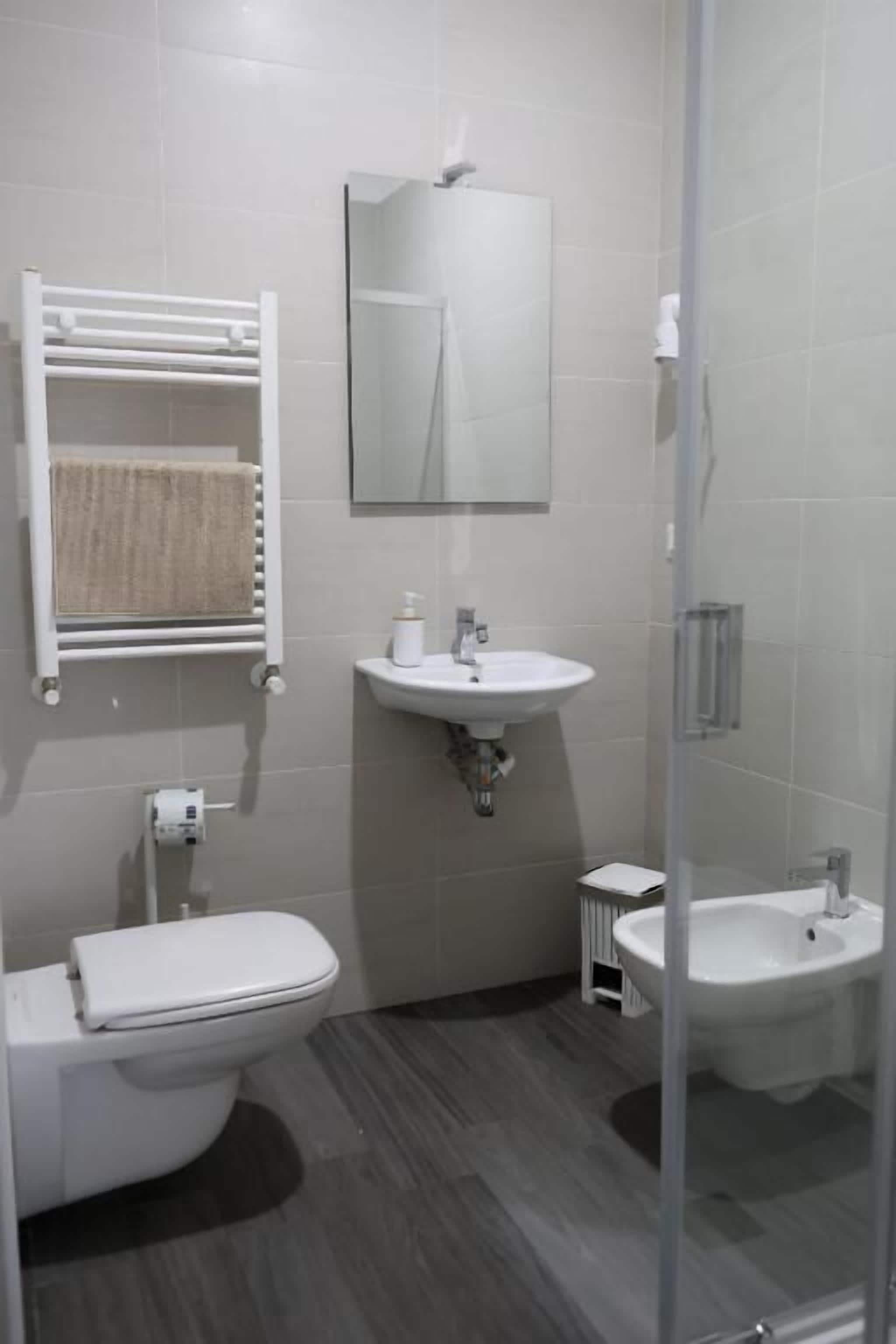 A modern bathroom with a toilet, sink, and bidet.