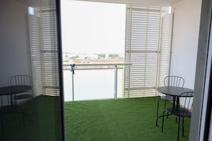 A room with a balcony, a table, and chairs.