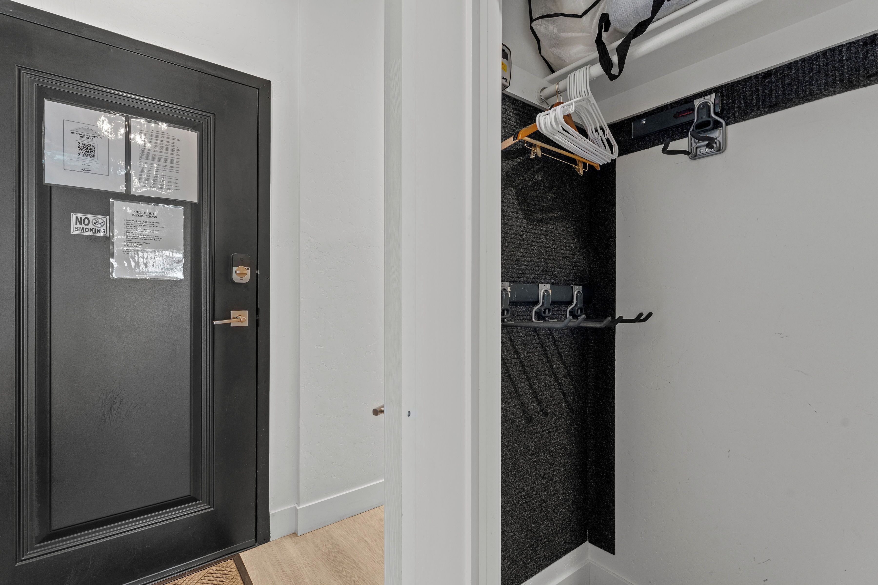 A room with a dark door, a white wall, and a shower area with a dark tiled wall.