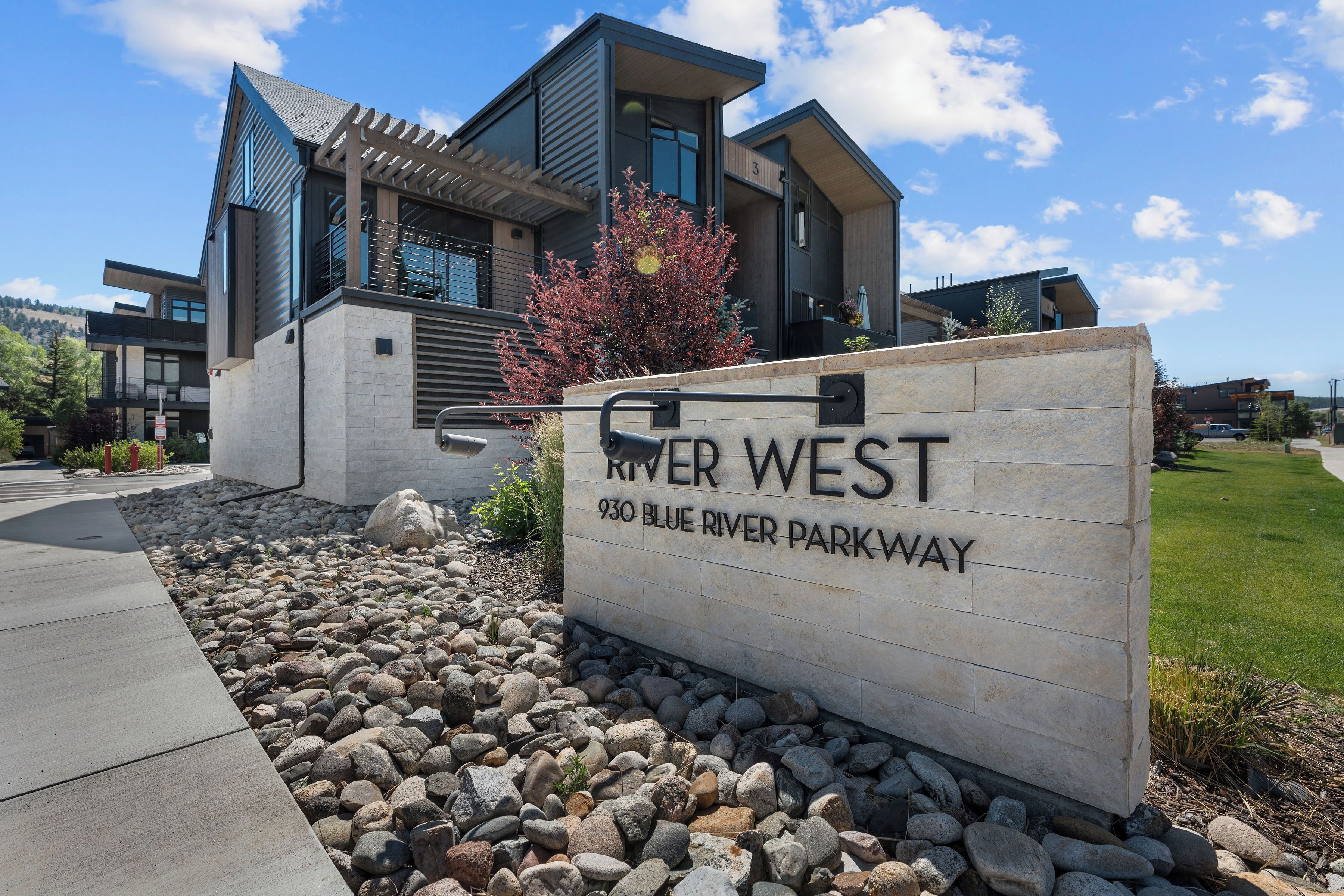 A modern building with a sign indicating 'River West 930 Blue River Parkway.'