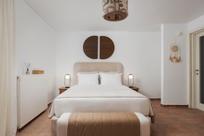 A bedroom with a bed, bedside lamps, a radiator, a dreamcatcher, and a door. - Villa Liberta Athenian Riviera (Saronikos)