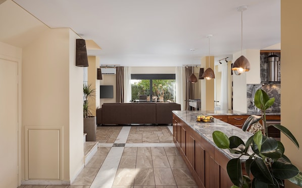 Una cocina moderna con una isla central, iluminación colgante y vistas al exterior.