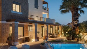 A modern two-story building with a pool, outdoor seating, and a palm tree. - Villa Liberta Athenian Riviera (Saronikos)