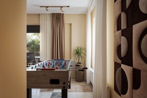 A room with a foosball table, a potted plant, and a view of the outdoors. - Villa Liberta Athenian Riviera (Saronikos)