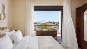 A hotel room with a bed, a wooden wardrobe, and a balcony with a wicker chair. - Villa Liberta Athenian Riviera (Saronikos)