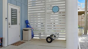 Eine überdachte Veranda mit einem Rollstuhl, einer Tür und einer Uhr an der Wand.