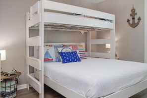 A bunk bed with a white frame, a lower bunk with a pull-out desk, and a headboard with nautical-themed pillows. - Cottage By The Sea (Port St. Joe)