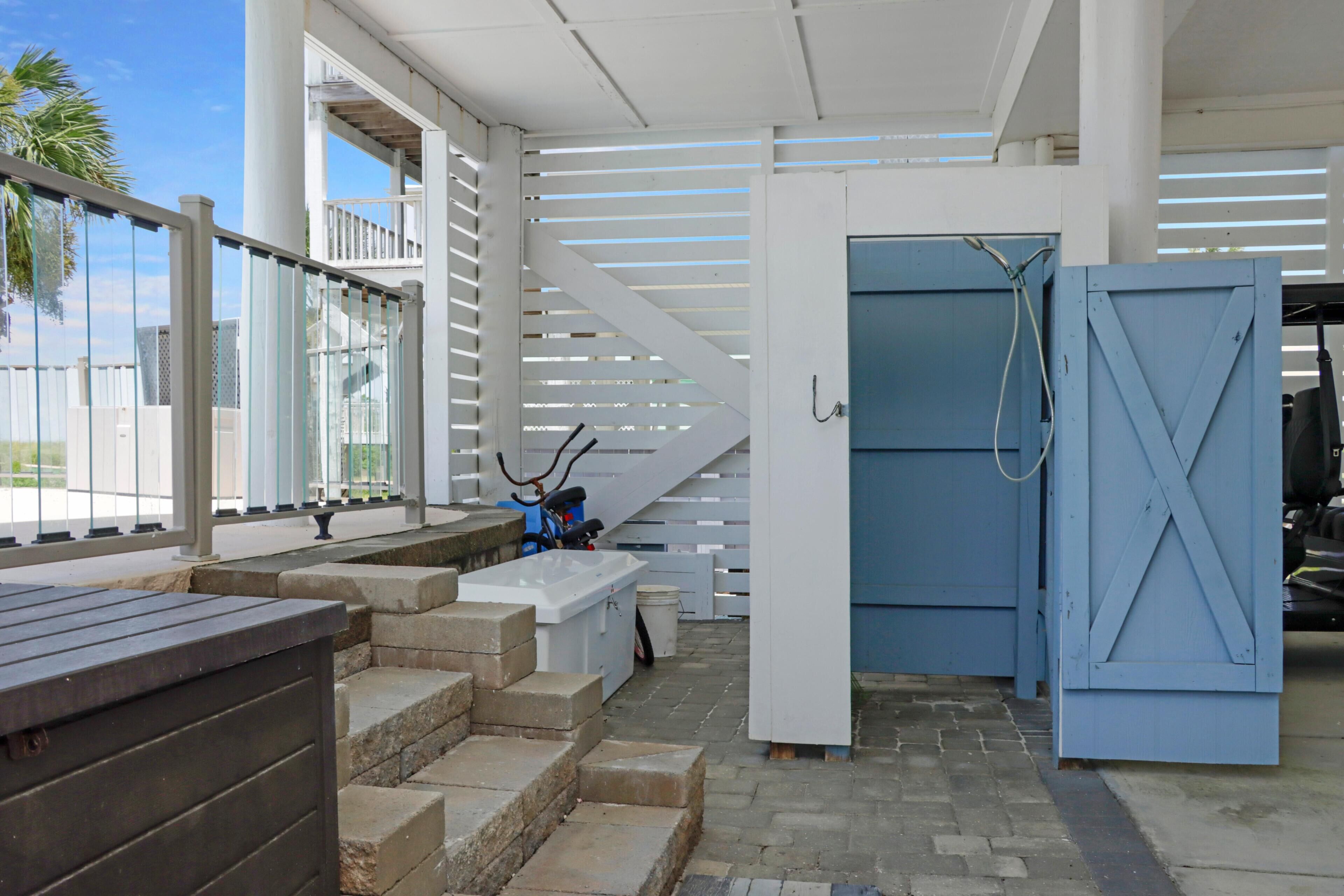 Un espace extérieur abrité, doté d’un escalier menant à une porte, d’un banc et offrant une vue sur le ciel.