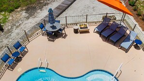 Ein Poolbereich mit Sprungbrett, Liegestühlen und einem Tisch mit Stühlen.