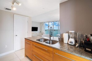 A modern kitchen with a large window, a built-in sink, and a blender on the counter. - Icon Brickell 2BR · Panoramic Bay Views, Sleeps 6 (Miami)