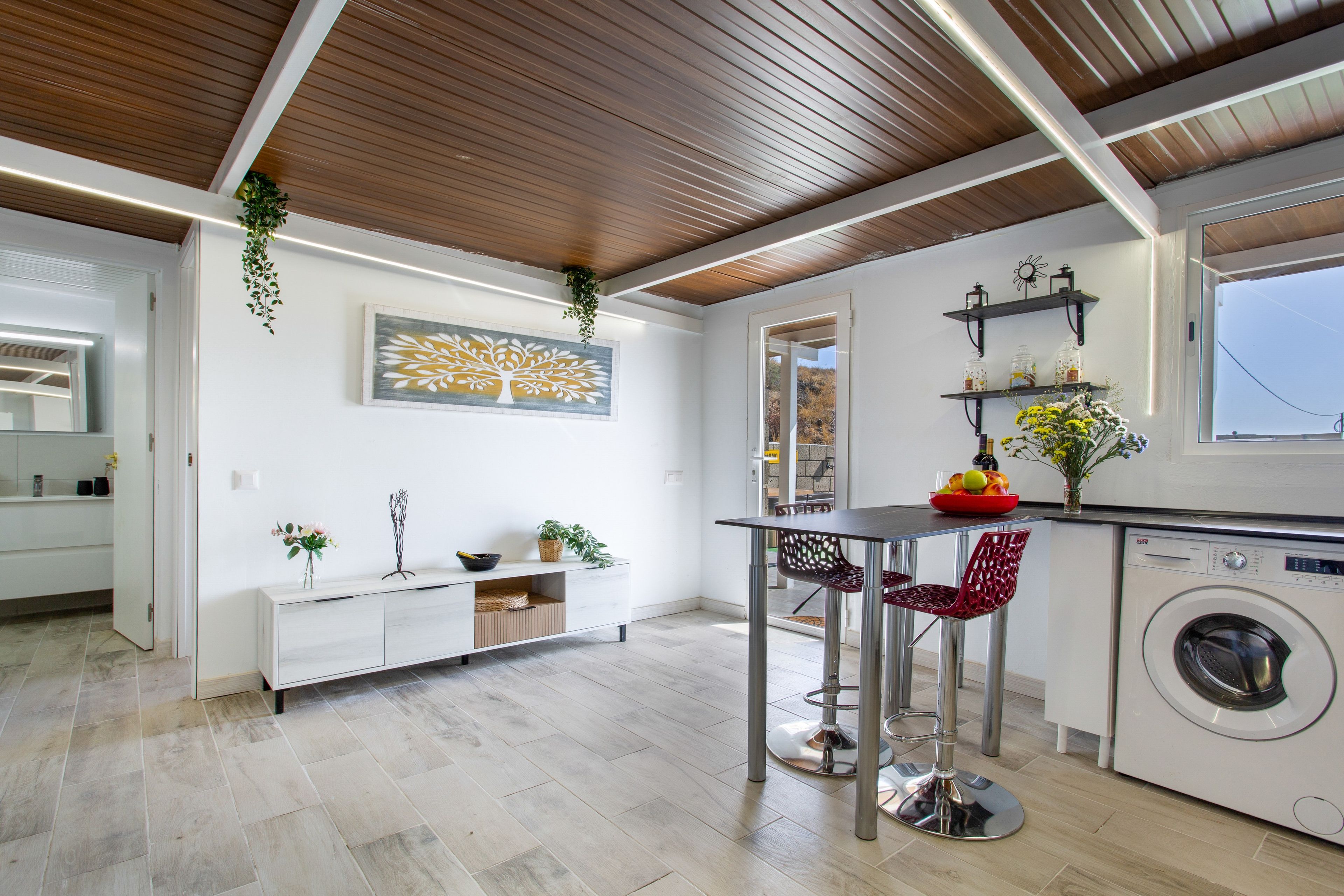 Una cocina moderna con una isla central, lavadora y comedor con sillas.
