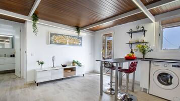 Una cocina moderna con una isla central, lavadora y comedor con sillas.