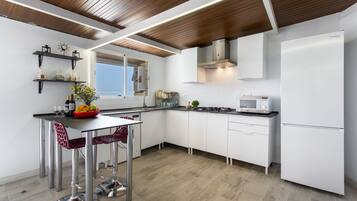 A modern kitchen with white cabinetry, stainless steel appliances, and a wooden ceiling.