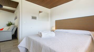 A bedroom with a bed, a nightstand, a lamp, a chair, and a wall-mounted picture.