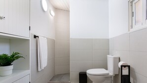 Ein kleines, weißes Badezimmer mit Toilette, Waschbecken, Handtuchhalter und einem Blumentopf.
