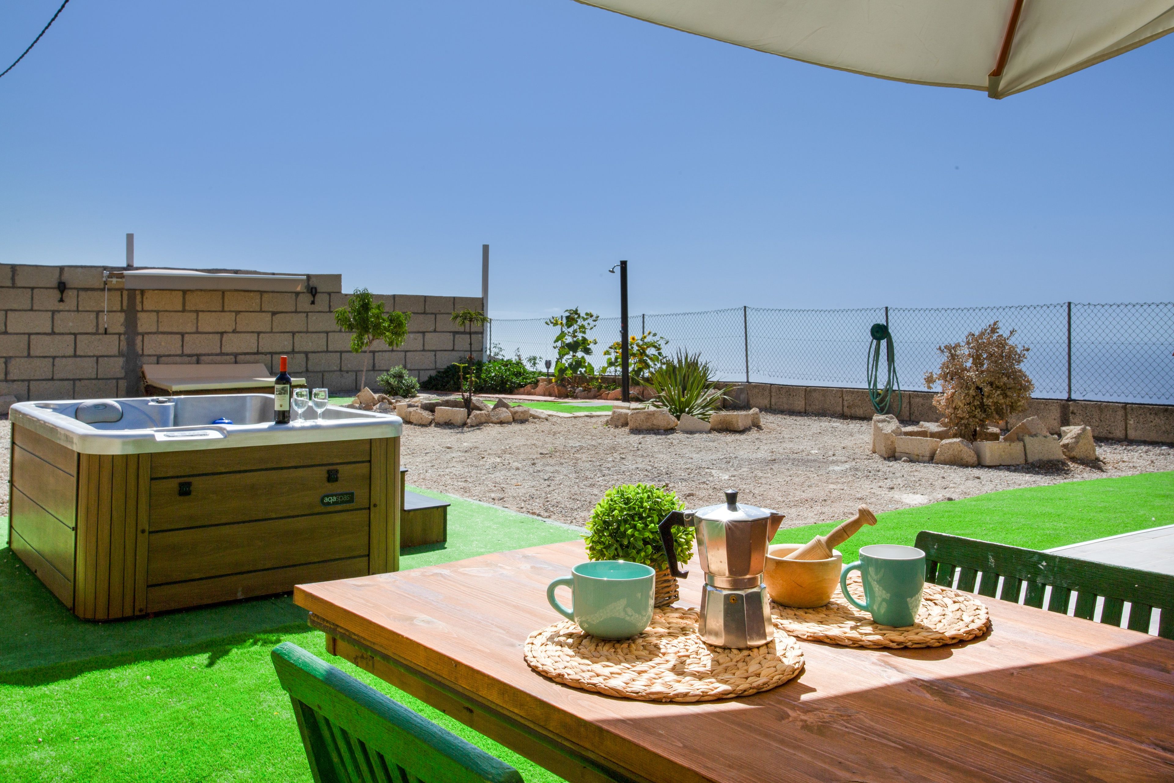 Une table en bois, un jacuzzi, un meuble en bois et une vue sur la plage.