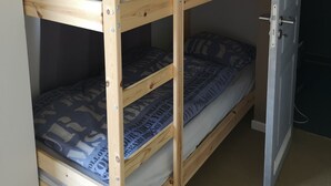A bunk bed with a pull-out desk and a door to the right.