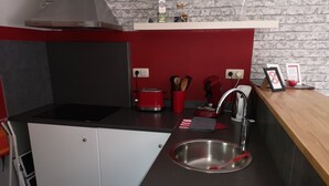 A modern kitchen with a stainless steel sink, a red toaster, and a knife block on the counter.