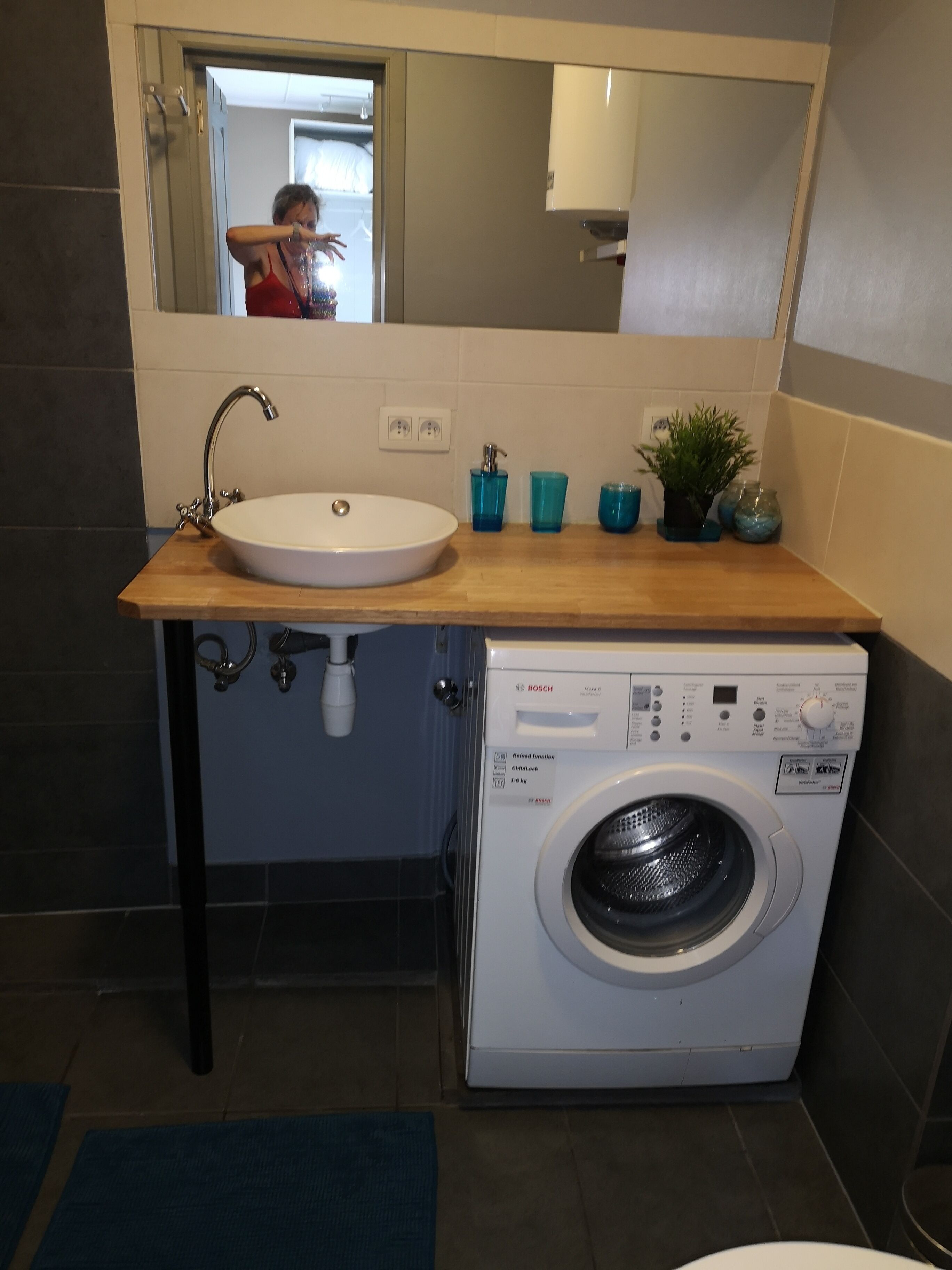 Une salle de bain avec un lavabo, un miroir et un lave-linge.