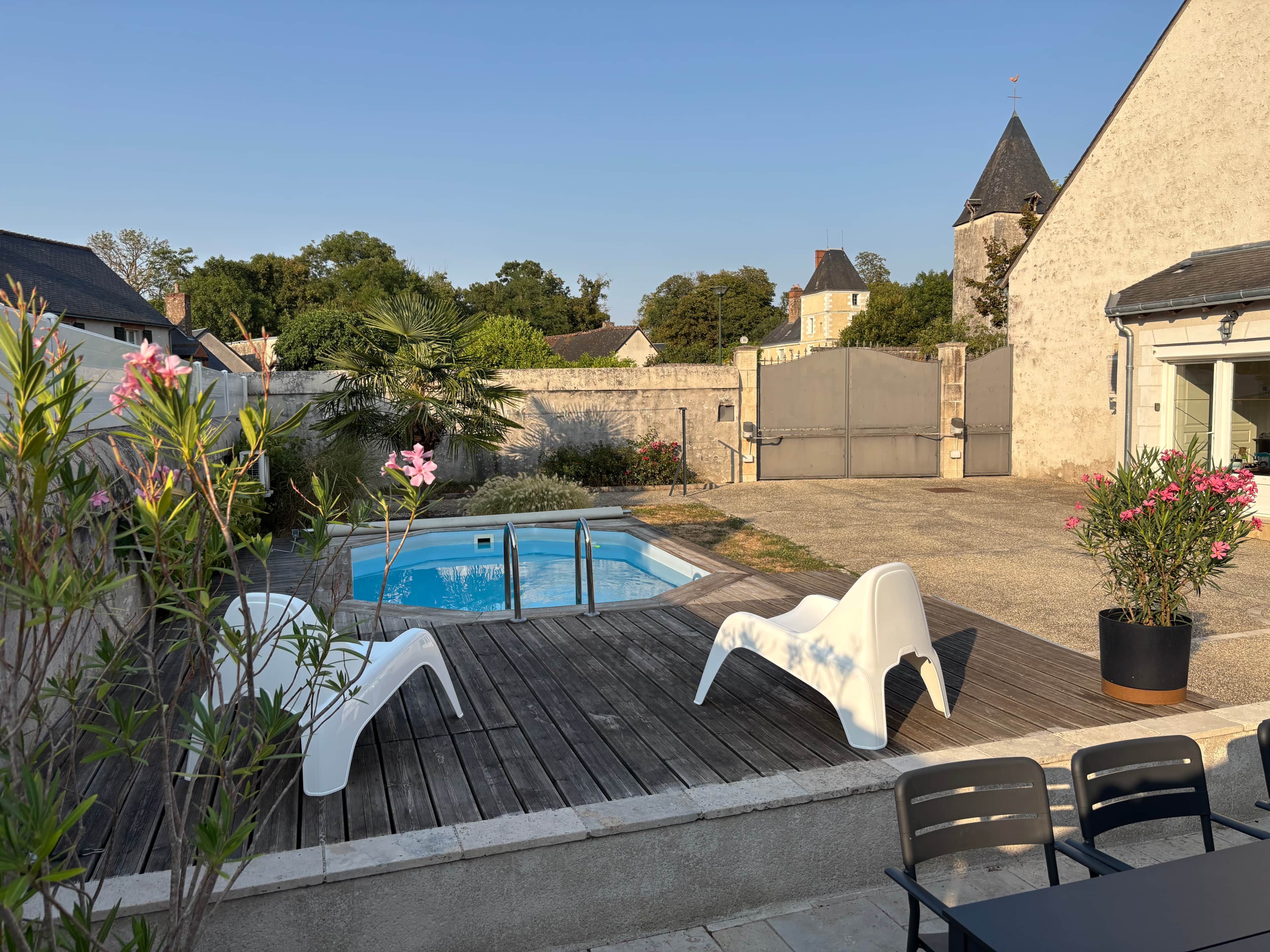 Um quintal com piscina, deck de madeira e área de estar externa.