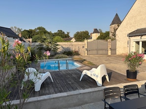 Um quintal com piscina, deck de madeira e área de estar externa.