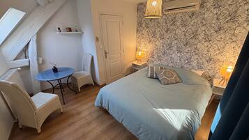 Een slaapkamer met een bed, twee stoelen, een klein tafeltje en een decoratieve wand.