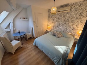 A bedroom with a bed, two chairs, a small table, and a decorative wall.